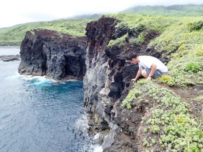 三宅島の観光スポットの崖で下をのぞき込んでいる様子。