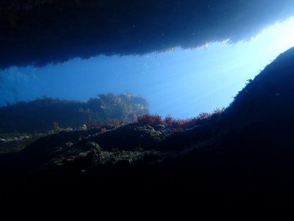 ダイビング中に水中で岩と岩の間から光が差し込んでいる様子