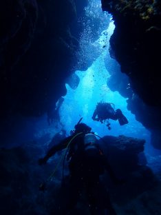 沖縄北部ダイビング。水中洞窟をダイバーが進んでいる様子